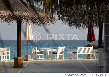 White empty table table and chairs at tropical resrraunt on open terrace in maldives. Blue ocean lagoon on background. No people. 113153991