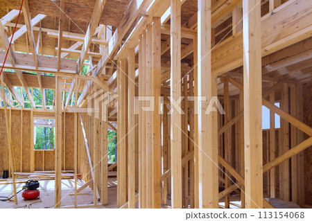 An unfinished residential home under construction with wood framing beam supporting it An unfinished residential home under construction with wood framing beam supporting it 113154068
