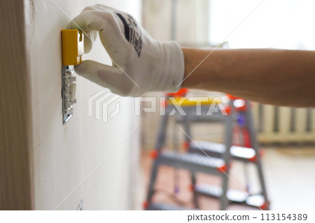 Leveling during the installation of a new electrical outlet on the wall during renovations 113154389