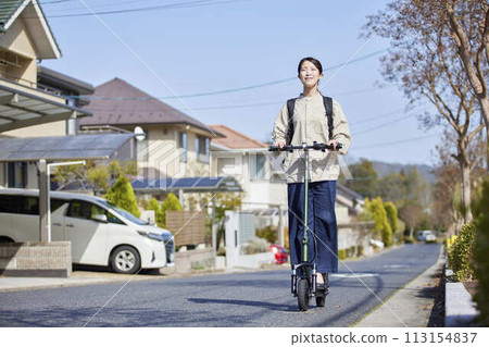A Japanese woman riding an electric scooter through a residential area 113154837