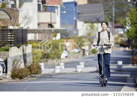 A Japanese woman riding an electric scooter through a residential area A Japanese woman riding an electric scooter through a residential area 113154839