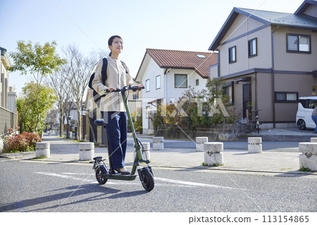 一名日本婦女騎著電動滑板車在住宅區走動 113154865
