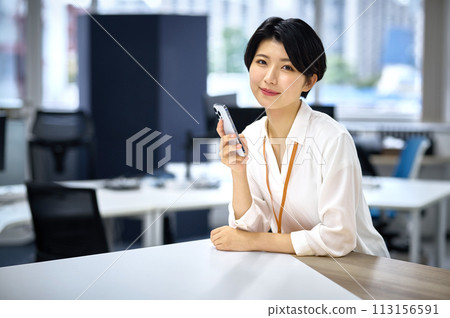 Young business woman operating a smartphone in the office 113156591