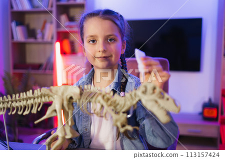 Happy preschool child gluing bones making model of tyrannosaurus at evening home Happy preschool child gluing bones making model of tyrannosaurus at evening home 113157424