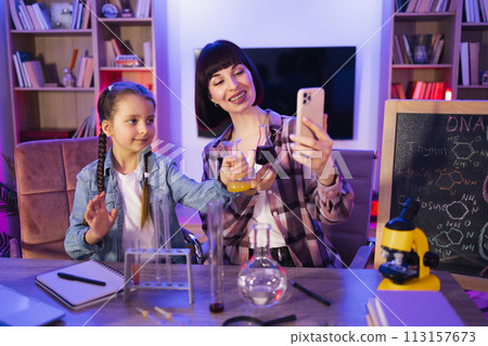 Happy mother making chemical experiments or tests with smart cute daughter. 113157673