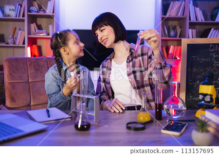 Happy mother educating little child daughter at home, making biological tests. Happy mother educating little child daughter at home, making biological tests. 113157695
