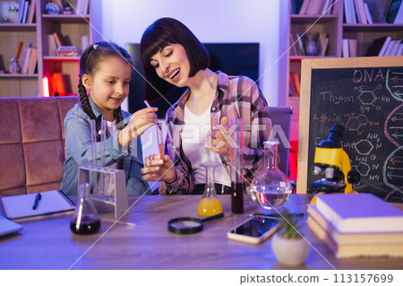 Parent mother with daughter kid making chemical test at evening time. Parent mother with daughter kid making chemical test at evening time. 113157699