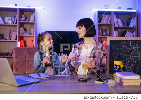 Kid girl playing with young mom, involved in doing chemistry experiments. Kid girl playing with young mom, involved in doing chemistry experiments. 113157718