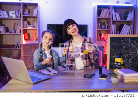 Mother teaching small kid girl doing chemical experiments at home. Mother teaching small kid girl doing chemical experiments at home. 113157721