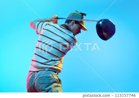 Rear view of man completing golf swing n mid follow-through with focus on club in neon light against gradient blue background. 113157746