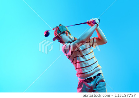 Male golf player on professional golf course. Golfer with golf club taking shot in neon light against gradient blue background. 113157757