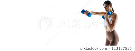 Banner. Young woman training hands with dumbbells against white studio background with negative space to insert text. 113157835