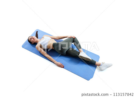 aerial view portrait of young brunette woman doing yoga exercises, stretching lying on mat against white studio background 113157842