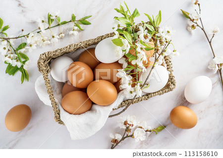 fresh natural chicken eggs in a wicker decorative basket, top view, spring 113158610