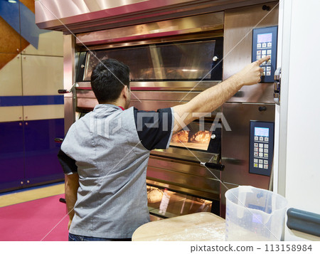 Man is baking bread in oven Man is baking bread in oven 113158984