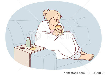 Woman sick with flu wrapped in blanket sits on couch and drinks hot decoction of herbs 113159030