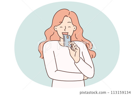 Woman brings credit card to face and smiles planning to make online purchase or pay for shopping 113159134