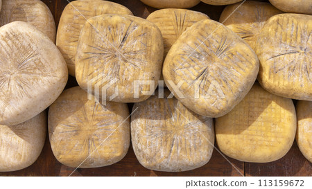 Artisanal Cheese Wheels Stacked at a Rustic Market Stall 113159672