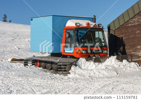 Red snowcat,  fully tracked vehicle designed to move on snow in front of ski lodge in krkonose mountains, Czech Republic. 113159781