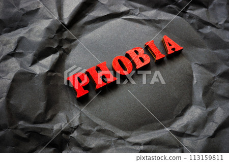 Black crumpled paper with the word phobia. 113159811