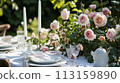 Table setting with rose flowers and candles for an event party or wedding reception in summer garden. 113159890