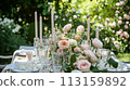 Table setting with rose flowers and candles for an event party or wedding reception in summer garden. 113159892
