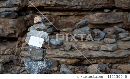 White bank card on a background of stones. The concept of bank reliability. 113159946