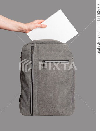 Hand putting blank book into backpack isolated Hand putting blank book into backpack isolated 113160629