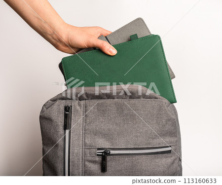 Hand putting books, planners, notebooks into backpack, schoolbag 113160633