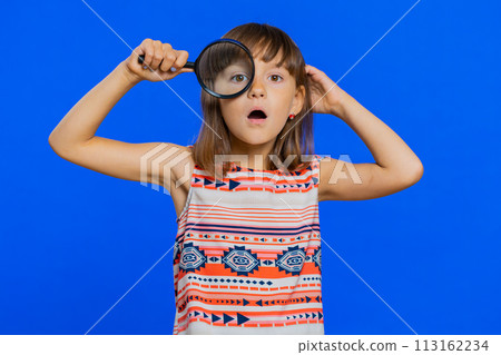 Child kid girl holding magnifying glass, looking into camera with big zoomed funny eye, analysing Child kid girl holding magnifying glass, looking into camera with big zoomed funny eye, analysing 113162234