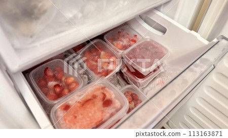 Freezer and frozen strawberries and raspberries in transparent plastic containers. Close-up 113163871