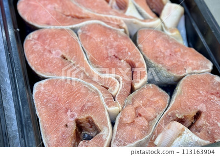 Atlantic salmon steaks from frozen raw materials on a substrate for sale in the supermarket. Close-up Atlantic salmon steaks from frozen raw materials on a substrate for sale in the supermarket. Close-up 113163904