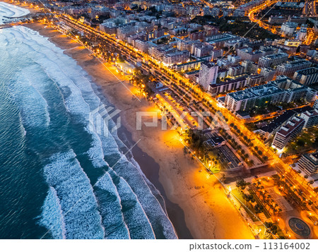 illuminated streets of Spanish touristic city Salou, Catalonia, aerial view of beach, sea and coast with palm trees, aerial view 113164002
