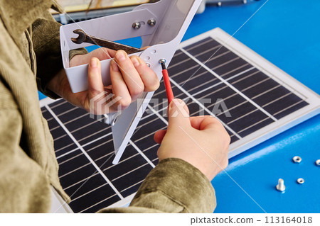 Electrician attaches mounting bracket to solar panel holder. Electrician attaches mounting bracket to solar panel holder. 113164018