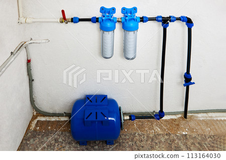 Pressure accumulator or reverse osmosis diaphragm storage tank, and string wound cartridge filters in home water supply system in utility room. 113164030