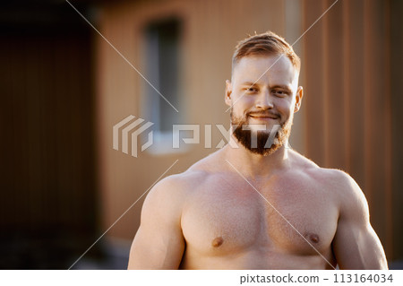 Muscular young European man without shirt outdoors in countryside near house. Muscular young European man without shirt outdoors in countryside near house. 113164034