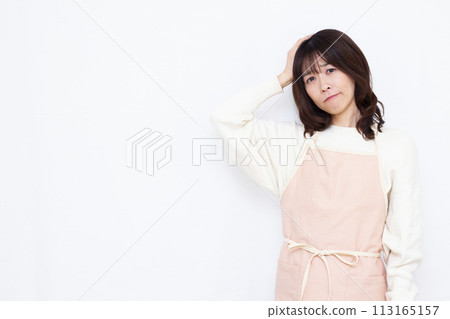 A housewife wearing an apron holding her head and worrying A housewife wearing an apron holding her head and worrying 113165157