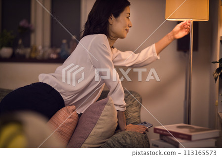 Night routine of a business woman who takes off her jacket and turns on the light at the stand. 113165573