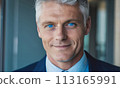 businessman, face of a blue-eyed gray-haired man, business concept, man smiling, head office employee, friendly employer, businessman sitting at his desk, gray-haired handsome man in a jacket smiling 113165991