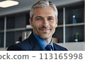 businessman, face of a blue-eyed gray-haired man, business concept, man smiling, head office employee, friendly employer, businessman sitting at his desk, gray-haired handsome man in a jacket smiling 113165998