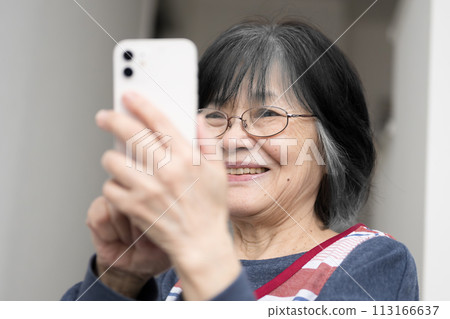 Senior woman looking at smartphone, smiling 113166637