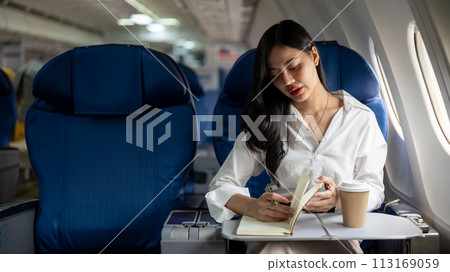 An elegant Asian businesswoman is on a plane, flying to another city for a business meeting. 113169059
