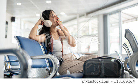 A female passenger is feeling sleepy while waiting for her boarding call. flight delayed 113169164