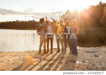 Group of Friends Enjoying a Beautiful Sunset by the Lake 113169417