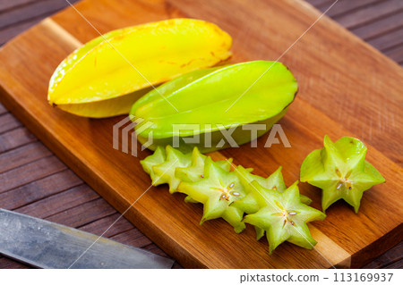 Whole and sliced fruits fresh carambola on table. Healthy vegetarian ingredient Whole and sliced fruits fresh carambola on table. Healthy vegetarian ingredient 113169937