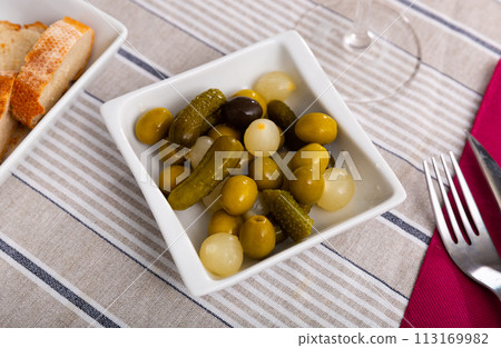 Marinated green olives, gherkins and pearl onions on plate 113169982
