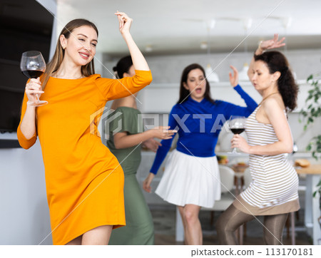 Cheerful woman dancing with wine glass at friendly house party Cheerful woman dancing with wine glass at friendly house party 113170181