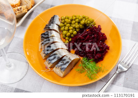 Slices herring fish with canned green peas, beetroot, decorated by mint served on plate with bread and cutlery Slices herring fish with canned green peas, beetroot, decorated by mint served on plate with bread and cutlery 113170191