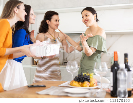 Asian woman greeting friends bringing gift for home party Asian woman greeting friends bringing gift for home party 113170193