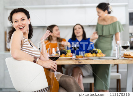 Happy Caucasian girl sitting in front of friends group, with her back to speakers. Happy Caucasian girl sitting in front of friends group, with her back to speakers. 113170216